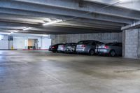 a large underground parking garage with several parked cars and concrete floors - free image for commercial use