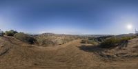 360 - view lens image of a boy riding on a motorcycle down a dirt trail