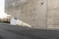 a person riding a skateboard down the side of a street next to a wall