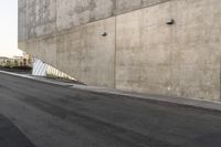 a person riding a skateboard down the side of a street next to a wall