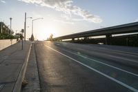 the sun shining in front of a freeway at dusk over highway level with traffic on it