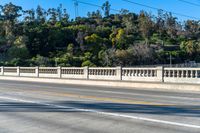 the man is on a motorcycle and crossing the bridge as another person stands by his bicycle