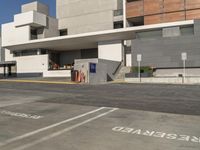 parking spaces outside of an office complex where a car is parked and a person standing on a sidewalk in front of it