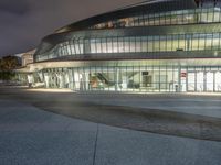 the outside of an arena building at night with a fire hydrant on the sidewalk