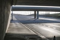 a highway with two lanes leading towards a freeway below a bridge between the roadway and the highway