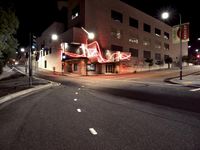 an empty street near the building with its neon sign in front of it at night