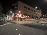 an empty street near the building with its neon sign in front of it at night