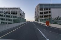 an empty road with many tall buildings in the distance on either side of it, in a big city