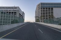 an empty road with many tall buildings in the distance on either side of it, in a big city