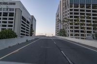 an empty road with many tall buildings in the distance on either side of it, in a big city