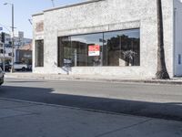 a man is walking past a restaurant on the side of the street behind a parked car