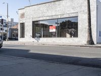 a man is walking past a restaurant on the side of the street behind a parked car