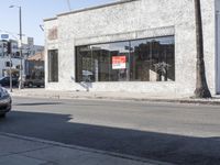 a man is walking past a restaurant on the side of the street behind a parked car