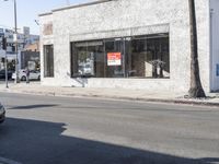 a man is walking past a restaurant on the side of the street behind a parked car