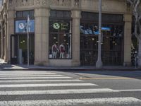 crosswalk at intersection of city street and building in urban area with traffic light, store window with windows, signs and bicycle