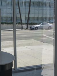 an empty street with cars out of window and in focus through glass doors at the sidewalk