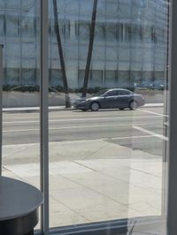 an empty street with cars out of window and in focus through glass doors at the sidewalk