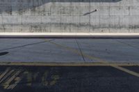 a man riding a red motorcycle down a street next to a cement wall and building