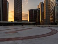 the setting sun illuminates a large circle on a concrete ground with a clock tower at top