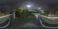 a street with some cars and an overpass and traffic lights at night, from a fish eye view