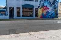 a large painting on the side of a building on the street and some cars parked