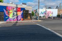 the building is painted with large paintings on it's side and behind it a stop sign