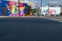 the building is painted with large paintings on it's side and behind it a stop sign