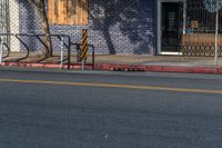 an empty street with three wooden chairs in front of a storefront window with a few people nearby