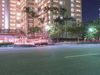 a tall white building with cars parked in front of it at night time on the streets