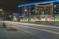 an empty street at night with some cars parked on the side of it and illuminated lights on