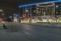 an empty street at night with some cars parked on the side of it and illuminated lights on