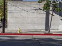 a red and yellow fire hydrant sitting on the side of a street corner next to a wall