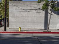 a red and yellow fire hydrant sitting on the side of a street corner next to a wall