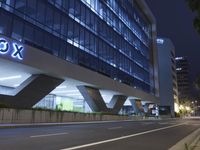 an illuminated building in the city at night and a street that has a median median