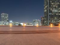 a very long view of some lights and buildings at night in the city with a skate board