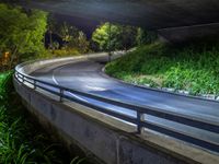 the view of an elevated highway lit up with street lights at night under a bridge