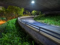 the view of an elevated highway lit up with street lights at night under a bridge