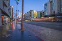 city street in the rain with buildings and traffic lights at night in front of a hollywood sign