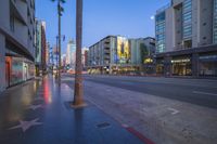 city street in the rain with buildings and traffic lights at night in front of a hollywood sign