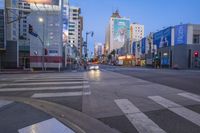 a city street filled with traffic and tall buildings at dusk time with a person crossing the sidewalk