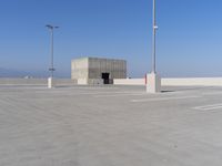 a parking lot with a large structure behind it with poles and lights in the corner