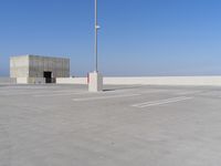 a parking lot with a large structure behind it with poles and lights in the corner