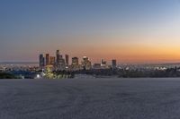 a view of the city skyline with mountains in the background at dusk or twilight from the top of a hill