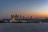 a view of the city skyline with mountains in the background at dusk or twilight from the top of a hill