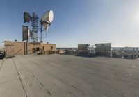 a small antenna sits on top of a building in an empty lot with buildings, and other commercial buildings