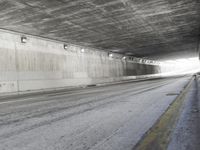 a black and white photograph shows a empty highway next to a tunnel that's been partially cut off