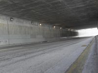 a black and white photograph shows a empty highway next to a tunnel that's been partially cut off