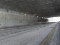 a black and white photograph shows a empty highway next to a tunnel that's been partially cut off