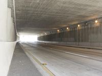 a black and white photograph shows a empty highway next to a tunnel that's been partially cut off