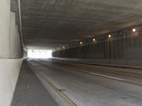 a black and white photograph shows a empty highway next to a tunnel that's been partially cut off